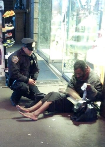 NYPD officer Lawrence Deprimo gives a homeless man boots. Photo via Jennifer Foster.