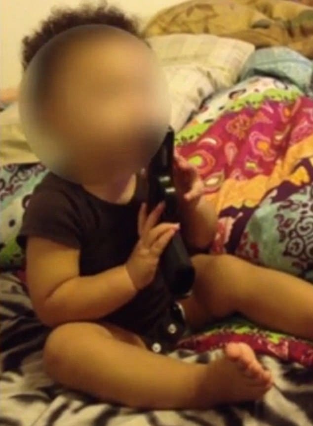 12 month old child playing with gun 