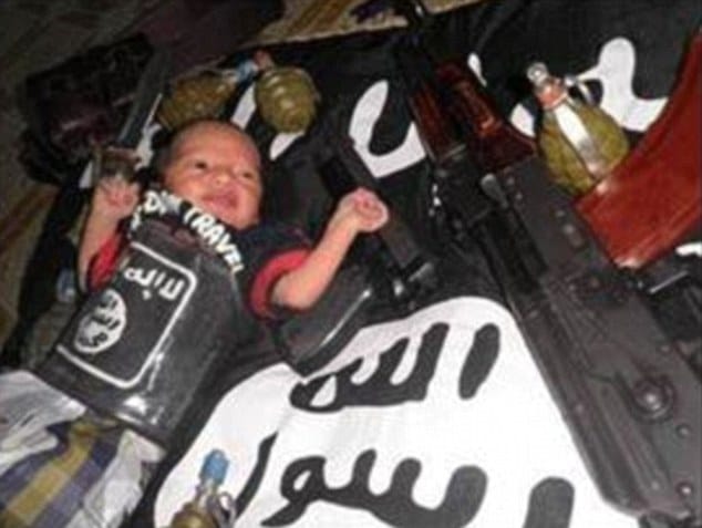 baby sleeping beside handgun and grenade underneath ISIS blanket
