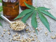 What Is CBD, and How Will It Affect Me? hemp leaves on wooden background, seeds, cannabis oil extracts in jars